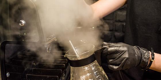 barista brewing coffee with steam emerging from glass kettle showing precise measurement for optimal 9 cup coffee preparation